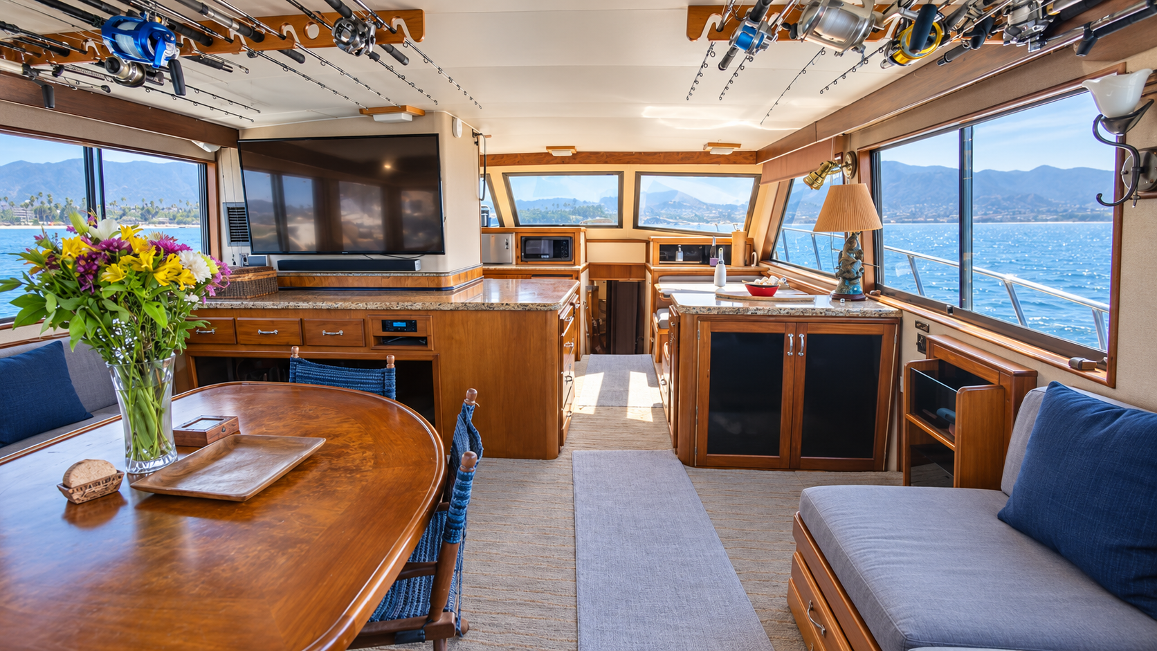 Sample yacht salon with dining space and fishing rods overhead