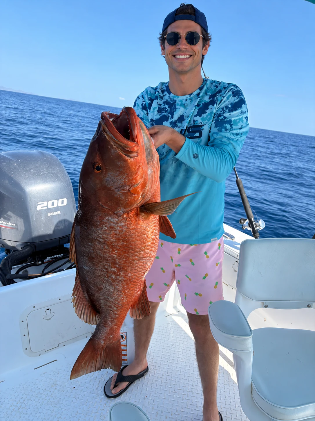 Angler holding a large snapper on a fishing boat